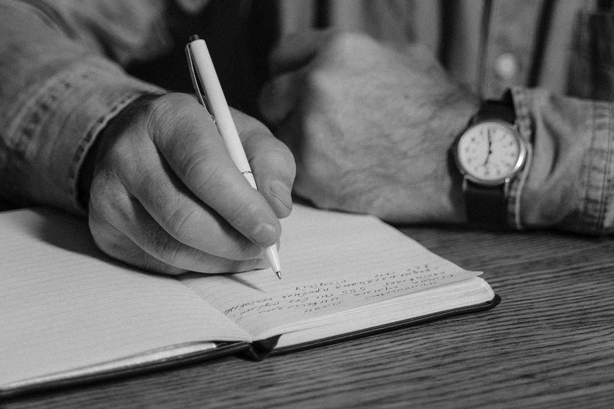 a man's hand writing in a journal