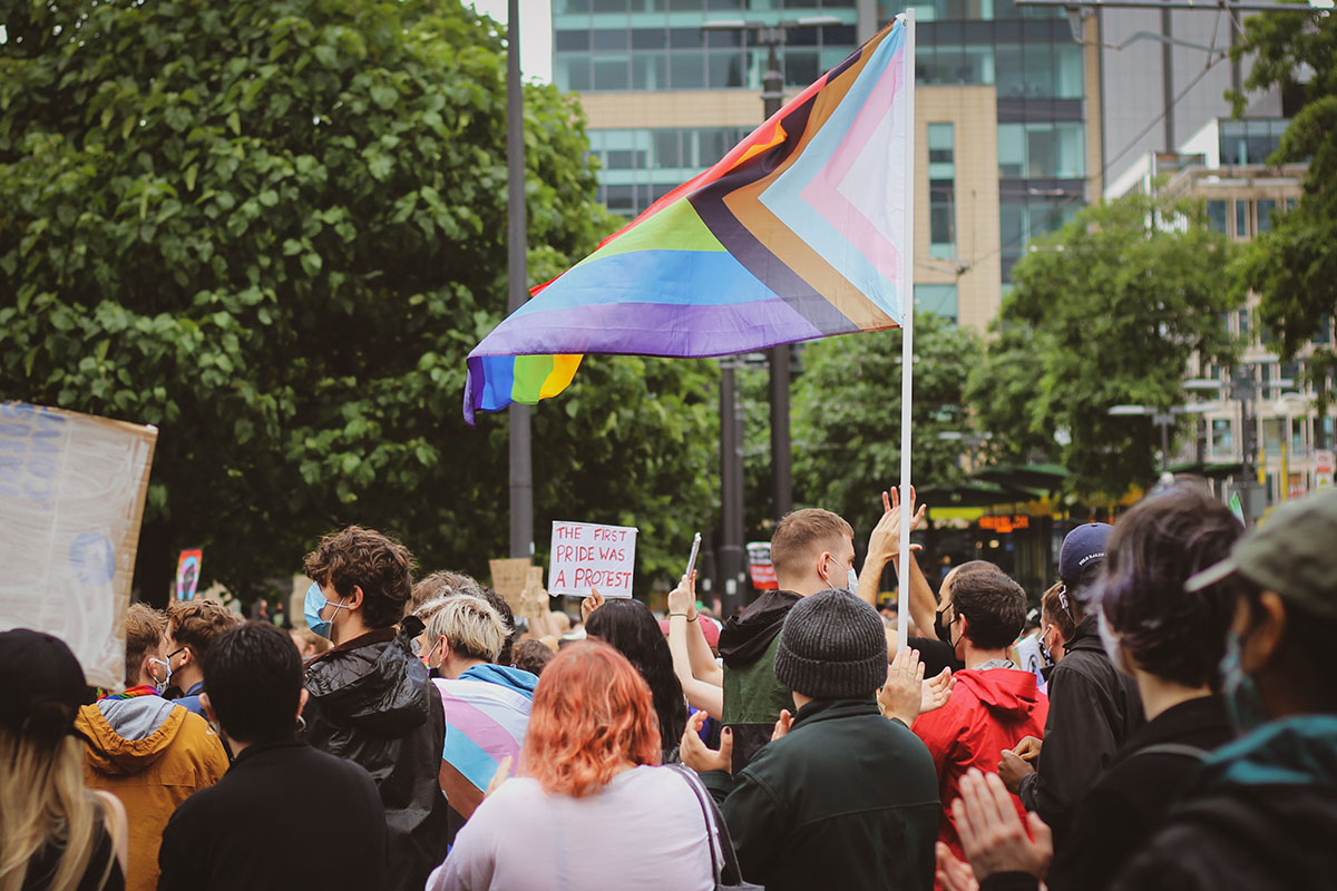 protest crowd with a LGBTQ flag