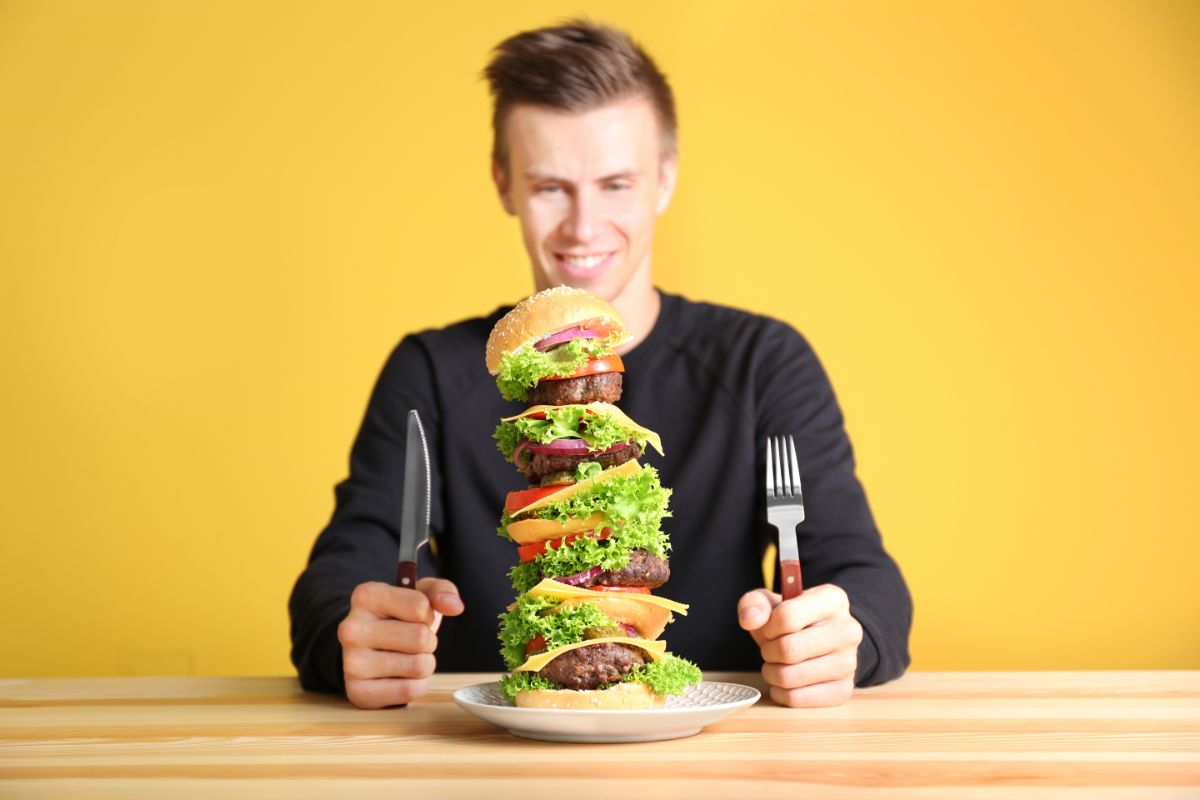 Man ready to eat a colossally tall sandwich